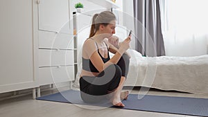 Young woman meditates at home. Yoga at home. Fitness online via smartphone. Sport exercises. Healthy lifestyle