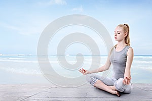 Young woman is meditating on the beach