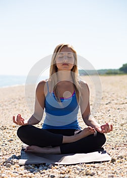 Young woman meditating at the beach