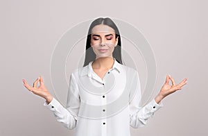 Young woman meditating on beige background. Stress relief exercise