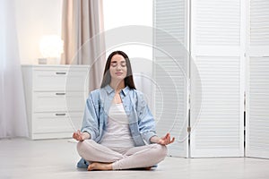 Young woman meditating on floor at home