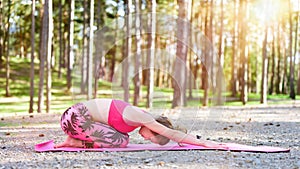 Young woman meditating in Hare position practicing yoga in a forest.