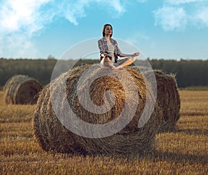 Young woman meditating on haystack