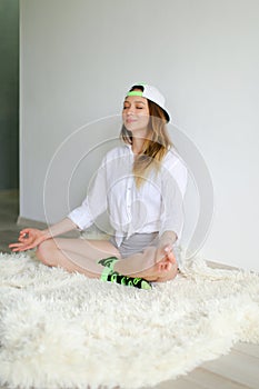 Young woman meditating at home and wearing cap.