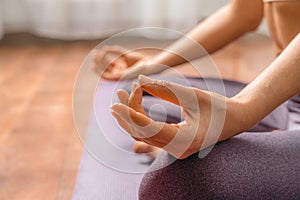 Young woman meditating in the lotus pose at home. Practicing yoga indoors. Harmony, yoga practice, balance, meditation