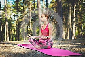 Young woman meditating in lotus position practicing yoga in a forest. Freedom concept. Relax, mind and body happiness