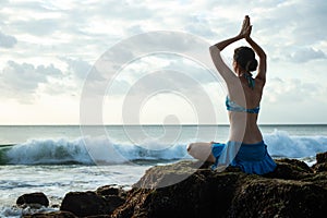 Young woman meditating, practicing yoga and pranayama with namaste mudra at the beach, Bali