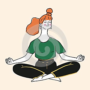 Young woman meditating. Redhead girl in bun sits cross-legged with her eyes closed, wears green shirt and black pants