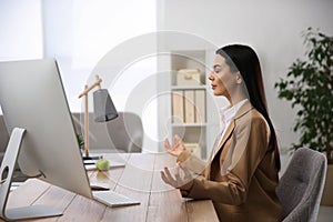 Young woman meditating at workplace. Stress relief exercise