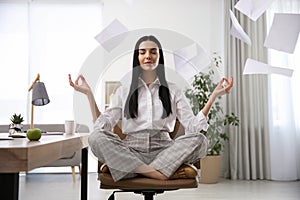 Young woman meditating at workplace. Stress relief exercise