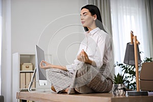 Young woman meditating at workplace. Stress relief exercise