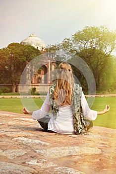 Young woman meditating in the yard of Humayun's Tomb. Delhi, Ind