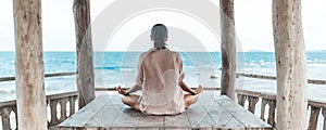 Young woman meditating in a yoga pose at the beach