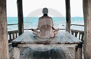 Young woman meditating in a yoga pose at the beach