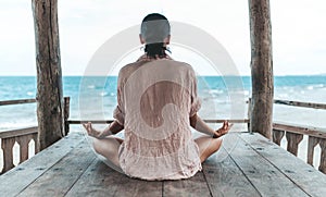 Young woman meditating in a yoga pose at the beach