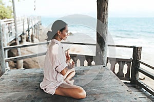 Young woman meditating in a yoga pose at the beach