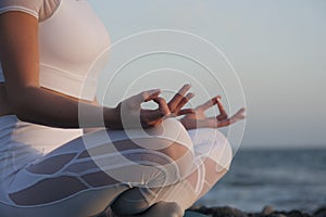 Young woman meditation in a yoga pose at the beach on sunset