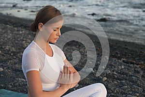 Young woman meditation in a yoga pose at the beach on sunset. Breathing practise