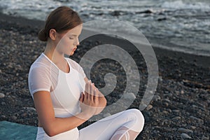 Young woman meditation in a yoga pose at the beach on sunset. Breathing practise