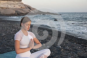 Young woman meditation in a yoga pose at the beach on sunset. Breathing practise