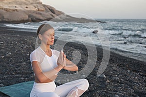 Young woman meditation in a yoga pose at the beach on sunset. Breathing practise
