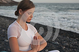 Young woman meditation in a yoga pose at the beach on sunset. Breathing practise