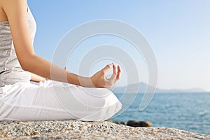 Young woman meditation in a yoga pose on the tropical beach.