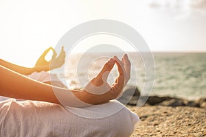 Young woman meditation yoga pose on tropical beach with sunlight