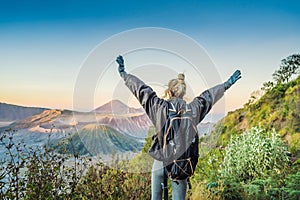 Young woman meets the sunrise at the Bromo Tengger Semeru National Park on the Java Island, Indonesia. She enjoys