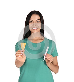 Young woman with menstrual cup and tampon on white background