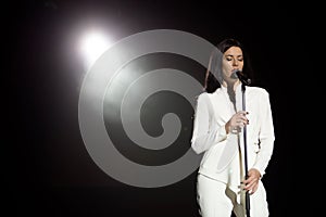 Young woman with microphone and white lights on a concert