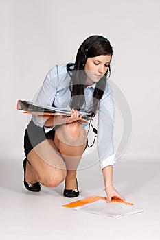 Young woman in mini skirt and blouse, squatting rises from the g