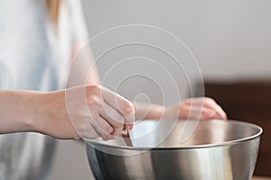 Young woman mixing chocolate in steel bowl to make candys