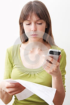 Young Woman With Mobile Phone And Bill Looking Worried