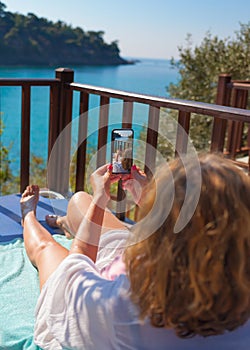 Young woman with a mobile phone in a deck chair