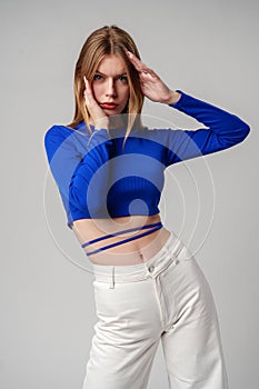 Young Woman model in Blue Top and White Pants posing on white background