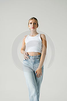 Young woman model is wearing a white tank top and blue jeans