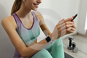 Young woman with modern smart watch and phone indoors, closeup