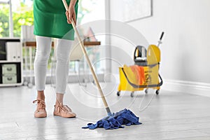 Young woman with mop cleaning floor