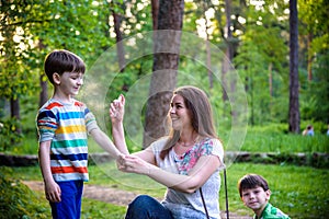 Young woman mother applying insect repellent to her two son before forest hike beautiful summer day or evening. Protecting