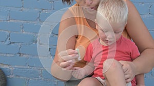 Young woman mother rubs a scratch on the baby`s knee with alcohol.