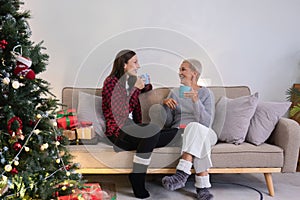 Young woman and mother sitting and talking in living room with Christmas tree and gift boxes. young woman talking Relax