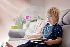 Young woman, mother with three kids, reading a book at home, hugging and laughing