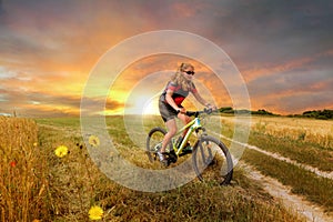 young woman mountain biking in the country lane in the evening in summer