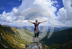 Young woman on the mountain with raised hands