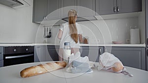 Young woman move bread, oatmeal, milk, vegetables from table to shelves. Zero waste home and eco bag. Eco Shopping.