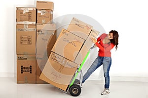 Young woman moving boxes with with a hand truck or dolly.