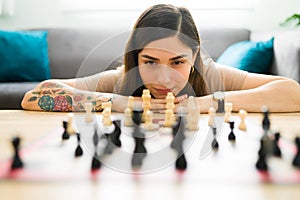 Young woman moving a chess piece on the coffee table