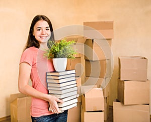 Young woman moving house to college, holding pile books and plan