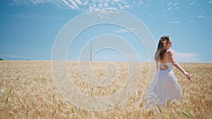Young woman moving spikelets meadow back view. Carefree girl running wheat field